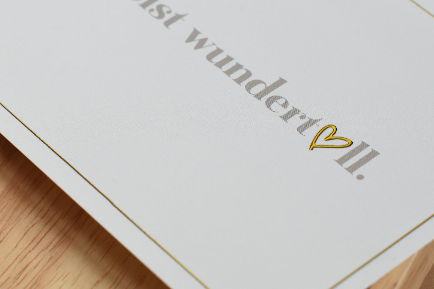 Detail einer weißen Postkarte mit dem Text 'Du bist wundertoll.' und einem goldfarbenen Herzsymbol
