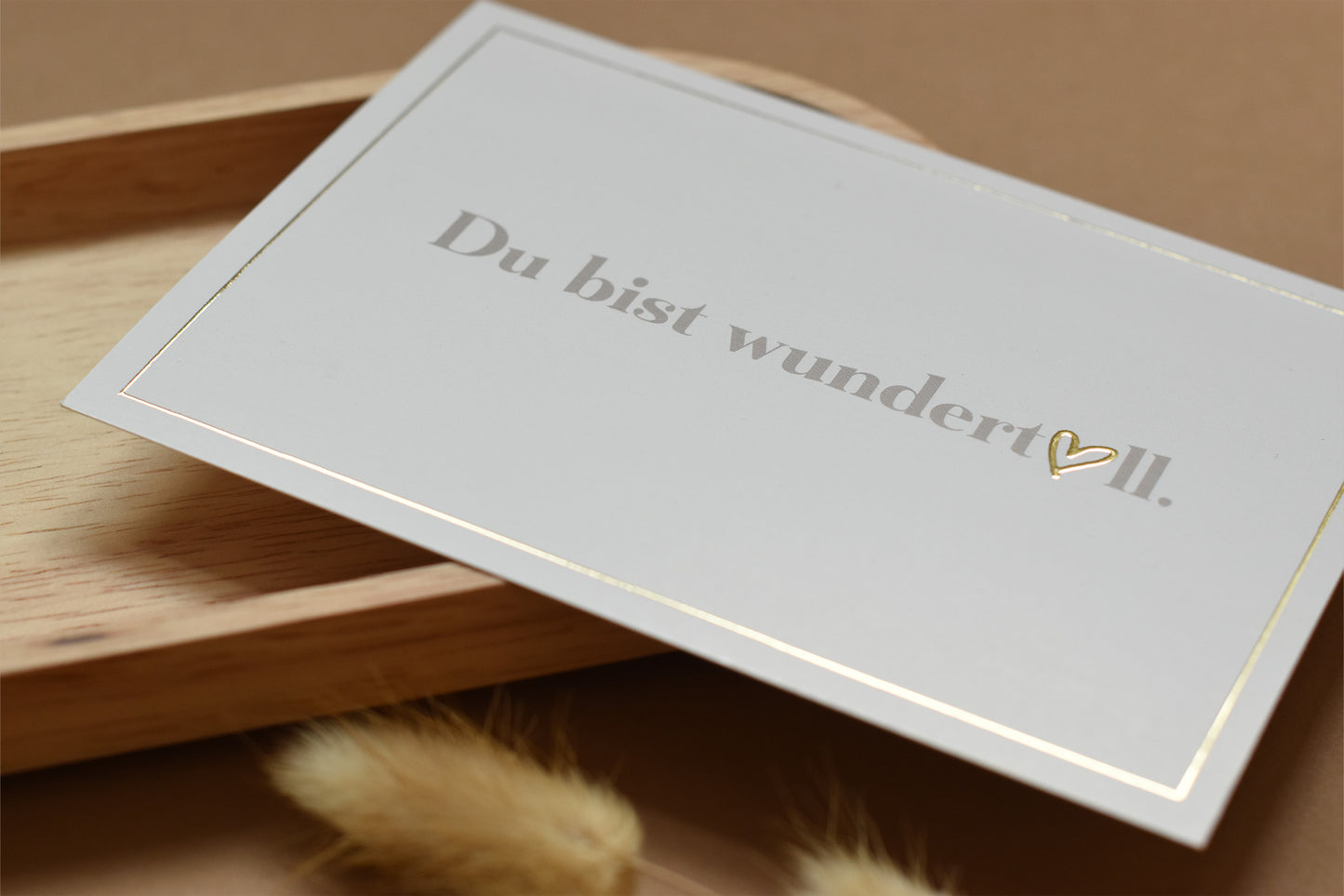 Helle Postkarte mit goldenem Rand und dem Schriftzug 'Du bist wundertoll.' mit einem goldenen Herz als Teil des Textes