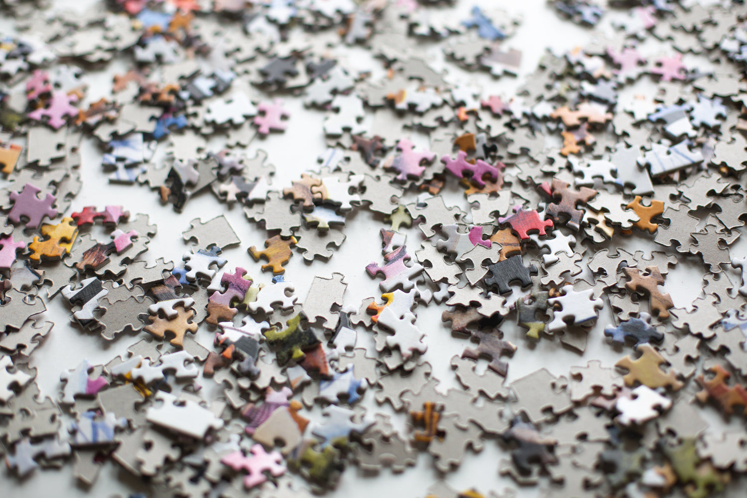 Viele bunte Puzzleteile verstreut auf einer weißen Oberfläche