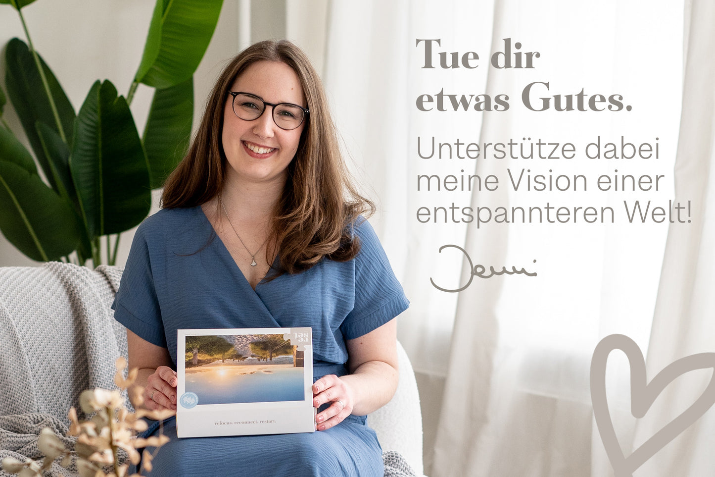 Frau in blauem Kleid sitzt auf Sofa und hält Produktverpackung mit Küstenspaziergang-Motiv, Text 'Tue dir etwas Gutes. Unterstütze dabei meine Vision einer entspannteren Welt!'