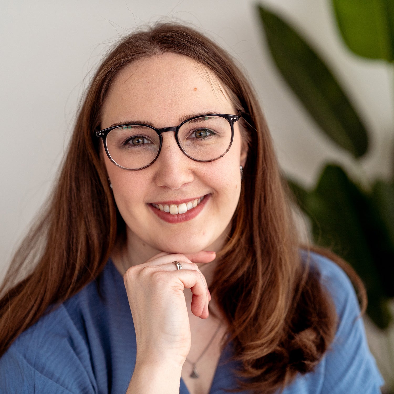 Porträt einer lächelnden Frau mit braunen Haaren, Brille und blauem Oberteil, die als Gründerin des Unternehmens dargestellt wird