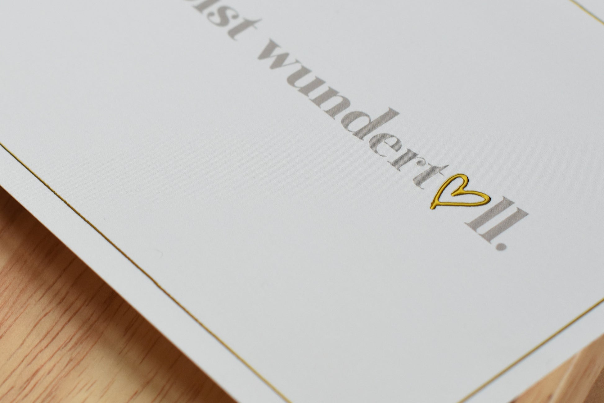 Detail einer weißen Postkarte mit dem Text 'Du bist wundertoll.' und einem goldfarbenen Herzsymbol
