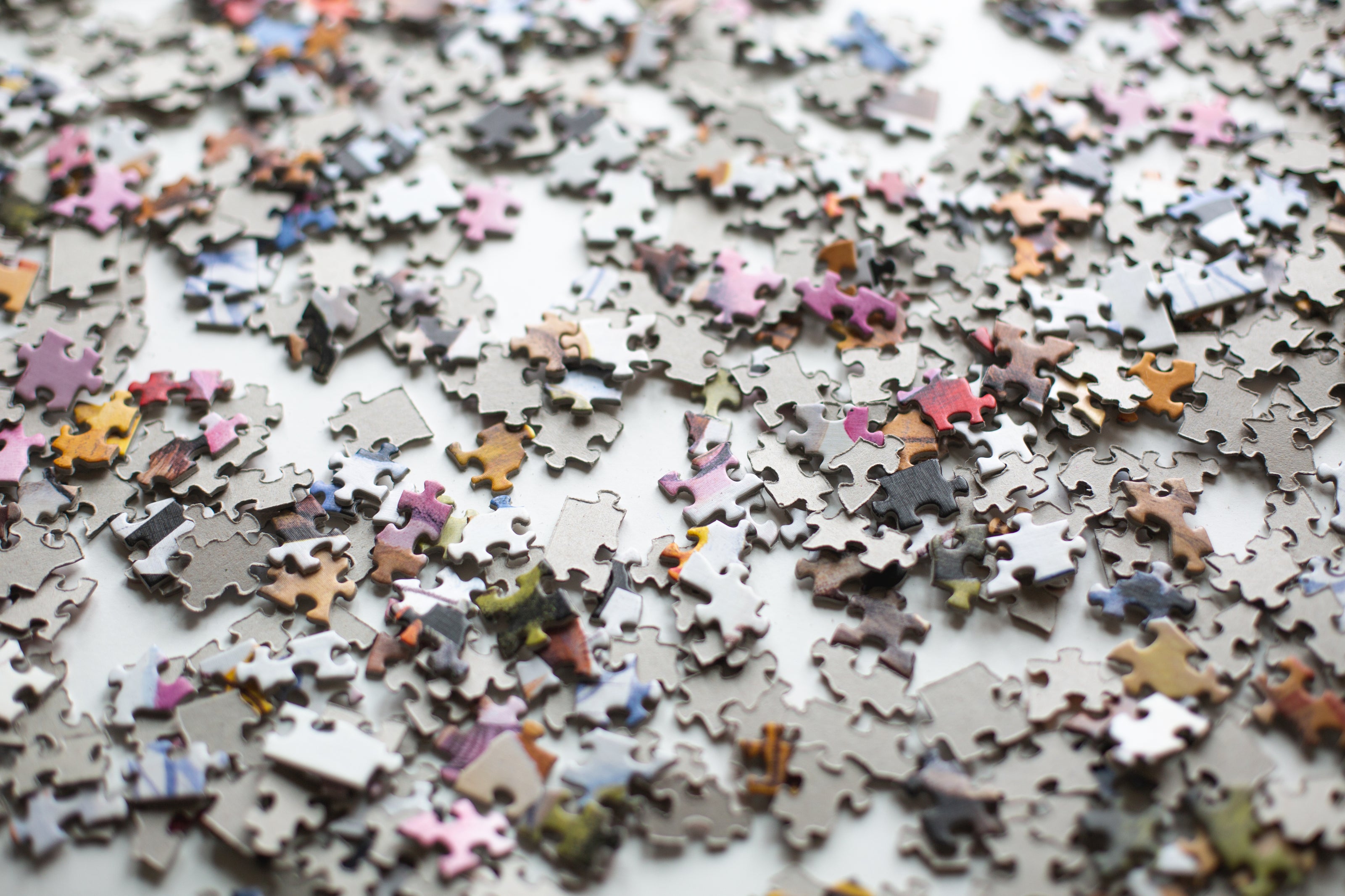 Viele bunte Puzzleteile verstreut auf einer weißen Oberfläche